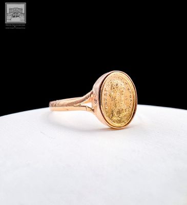a close up of a gold coin ring on a white surface