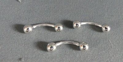 two silver metal nose piercings on a gray surface