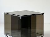 an image of a black glass table with wheels on a white surface