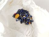 a small pile of blue and yellow beads on a white cloth