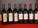 six bottles of wine are lined up on a red table