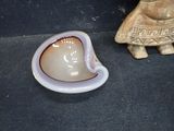 a small shell shaped object on the ground next to a figurine