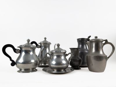 a group of silver teapots and cups on a white surface