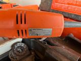 a close up of an orange corded drill on a table