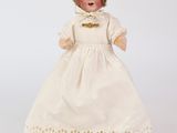 une poupée ancienne en porcelaine représentant une femme vêtue d'une robe blanche et d'un bonnet