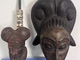 deux masques en bois posés l'un à côté de l'autre sur un socle bleu