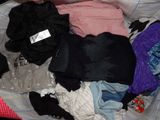 a pile of clothes that is sitting on a bed