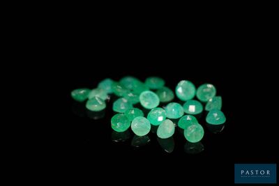 a close up of a bunch of green emeralds on a black surface