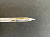 someone is holding a pencil with a rusted handle on a table