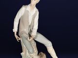porcelain figurine of a man sitting on a rock with a dog