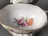 a figurine of a woman holding a bowl with flowers on it