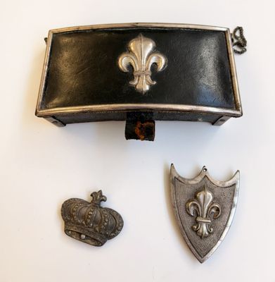 un sac à main noir orné d'une couronne, à côté de deux autres objets
