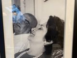 black and white photograph of a woman kissing a man in a room