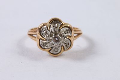 un gros plan sur une bague en forme de fleur, en or et sertie de diamants