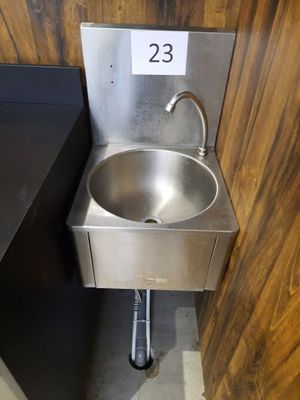 a stainless steel sink in the corner of a bathroom