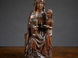 une statue en bois représentant une femme tenant un enfant dans ses bras, posée sur une table