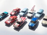 several toy cars are lined up in a row on a white surface