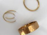 two gold rings and a gold ring on a white surface