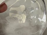 a person holding a clear glass bottle with a mickey mouse design on it