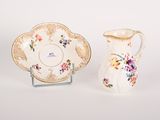 a small pitcher and a small plate sitting next to each other