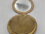 a close up of a gold compact mirror on a white surface