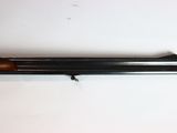 a shotgun with a wooden handle on a white surface