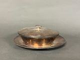 a silver plate with a lid on a gray surface