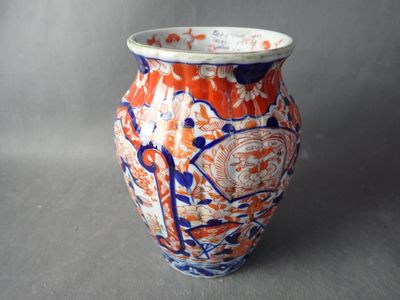 un vase orange et bleu posé sur une surface grise
