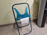 une chaise pliante bleue sur laquelle est posé un rouleau de papier toilette