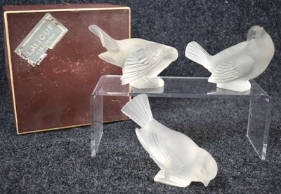 three glass birds sitting on a clear table