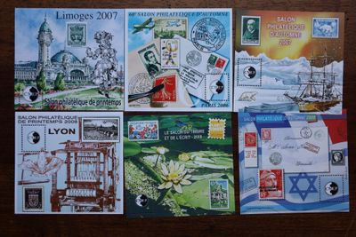 plusieurs timbres différents posés sur une table en bois sur laquelle figure l'image d'un bâtiment