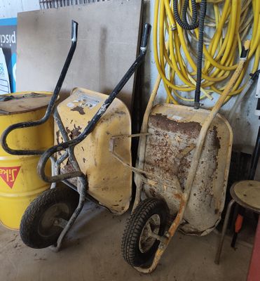 deux fûts jaunes et une brouette jaune dans un garage