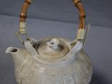 a tea pot with a bamboo handle on a table