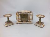 une petite horloge posée sur une table, à côté de deux bougies