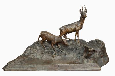 bronze sculpture of two deers on a rock with a white background