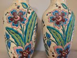 deux vases avec des fleurs peintes dessus, posés sur une table