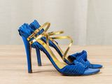 blue and gold high heeled sandals with ruffles on a wooden surface