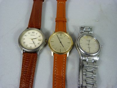 trois montres sont posées sur une surface blanche et sont dotées d'un bracelet marron