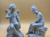 pair of statues of a boy and a girl sitting on a rock