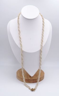 un mannequin blanc portant un collier, posé sur un socle en bois