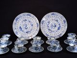 plusieurs assiettes, tasses et soucoupes bleues et blanches posées sur un fond noir