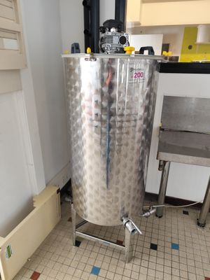 une cuve en acier inoxydable posée sur un sol carrelé dans une cuisine