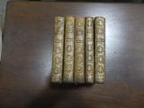 Trois vieux livres sont posés les uns à côté des autres sur une table en bois.