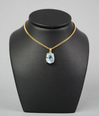 un collier en or orné d'une topaze bleue, posé sur un mannequin