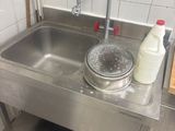 a stainless steel sink in a kitchen with a bottle of milk