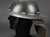 an old helmet on a mannequin head on a gray background