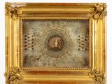 un cadre doré contenant une horloge, posé sur une surface blanche