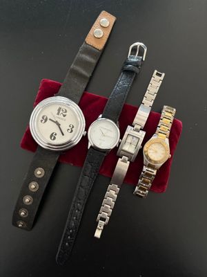 three watches are sitting on a red velvet bag on a black surface