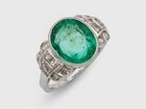 gros plan d'une bague avec une pierre verte entourée de diamants