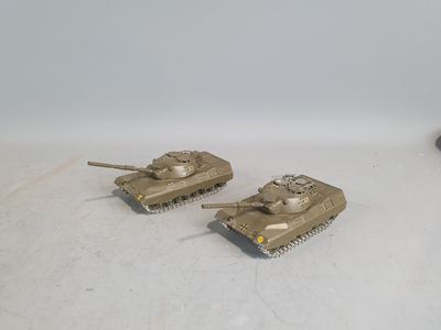 two toy tanks sitting next to each other on a white surface